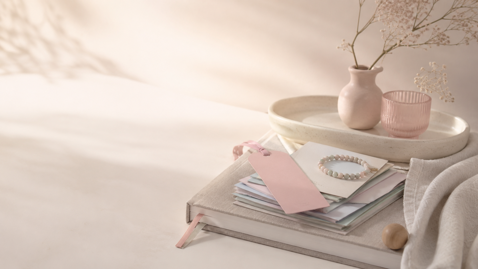 A Momsora journal with a blush gift tag, ceramic tray and beaded bracelet in soft daylight